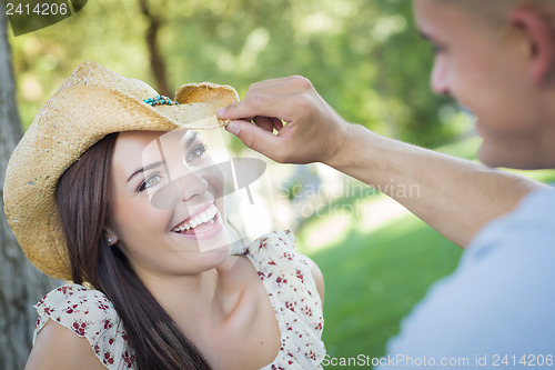 Image of Mixed Race Romantic Couple with Cowboy Hat Flirting in Park