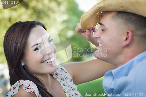 Image of Mixed Race Romantic Couple with Cowboy Hat Flirting in Park