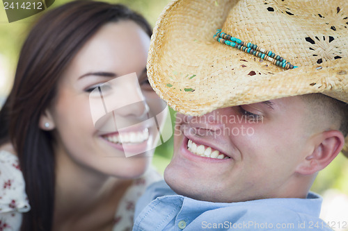 Image of Mixed Race Romantic Couple with Cowboy Hat Flirting in Park