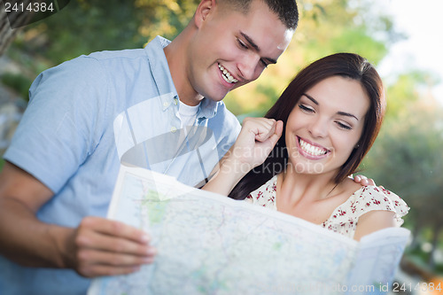 Image of Mixed Race Couple Looking Over Map Outside Together