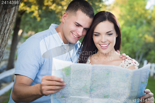 Image of Mixed Race Couple Looking Over Map Outside Together