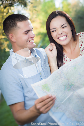 Image of Mixed Race Couple Looking Over Map Outside Together