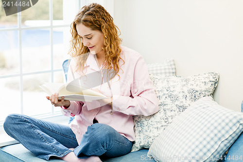 Image of Woman reading book by window