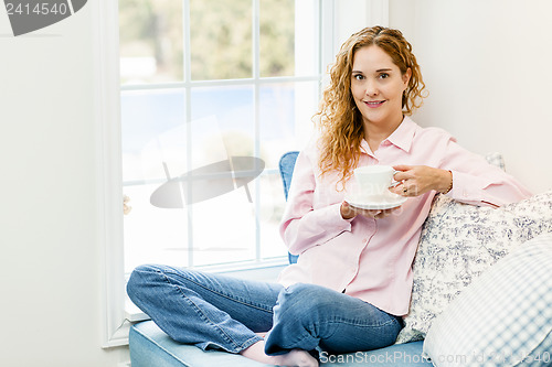Image of Woman relaxing by the window with beverage