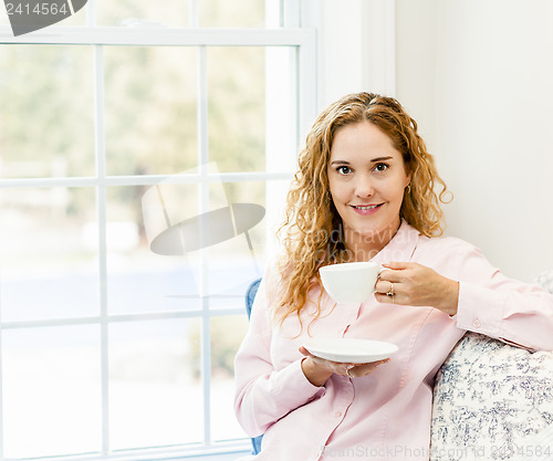 Image of Woman relaxing by the window with beverage