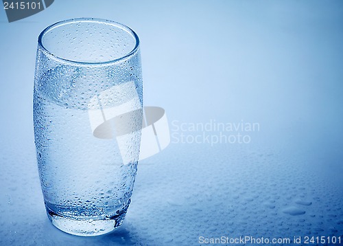 Image of wet glass of water on blue background