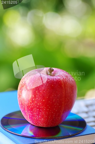 Image of Red apple and DVD on  books 