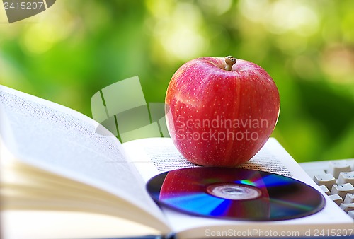 Image of Ripe apple, dvd, and open book 