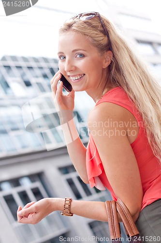 Image of attractive young blonde woman talking on the phone outdoor