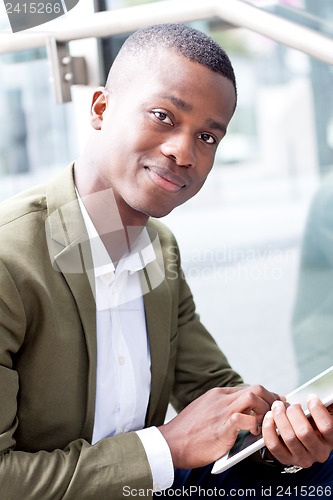 Image of smiling successful businessman with tablet pc outdoor