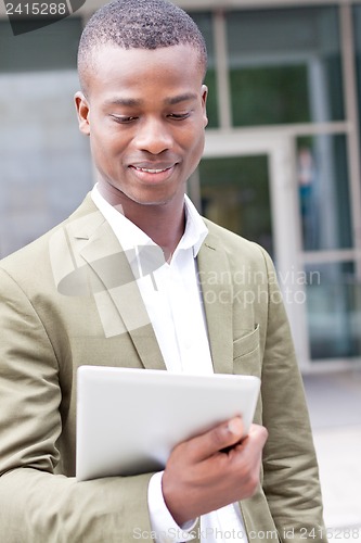 Image of smiling successful businessman with tablet pc outdoor