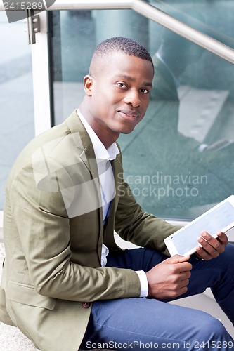 Image of smiling successful businessman with tablet pc outdoor