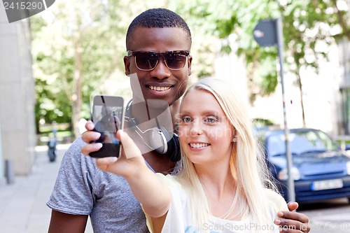 Image of young smiling multiracial couple taking foto by smartphone 