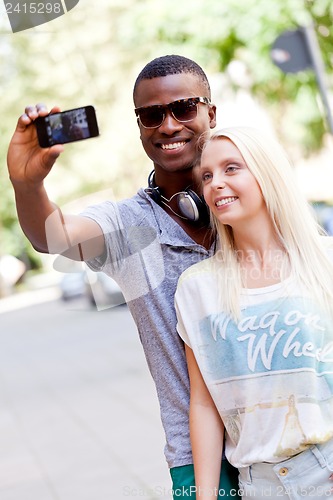 Image of young smiling multiracial couple taking foto by smartphone 