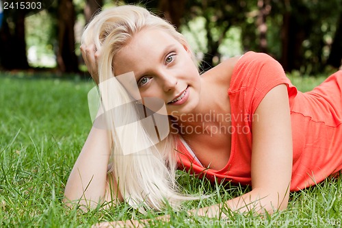 Image of beautiful young blonde girl lying in grass summertime