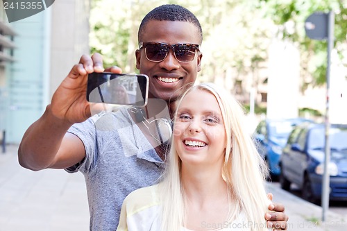 Image of young smiling multiracial couple taking foto by smartphone 