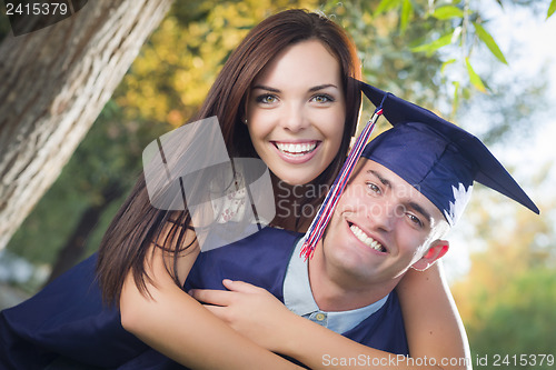 Image of Male Graduate in Cap and Gown and Girl Celebrate