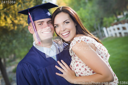 Image of Male Graduate in Cap and Gown and Girl Celebrate