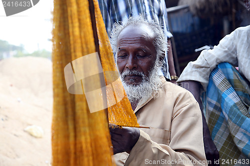 Image of Fisherman who weaves a fishing net before the next fishing in Kumrokhali, West Bengal, India.