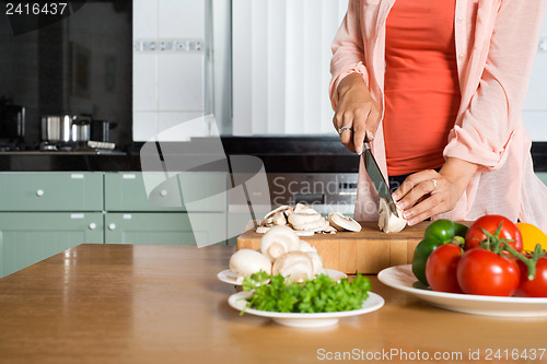 Image of Midsection Of Woman Cutting Vegetables At Kitchen Counter