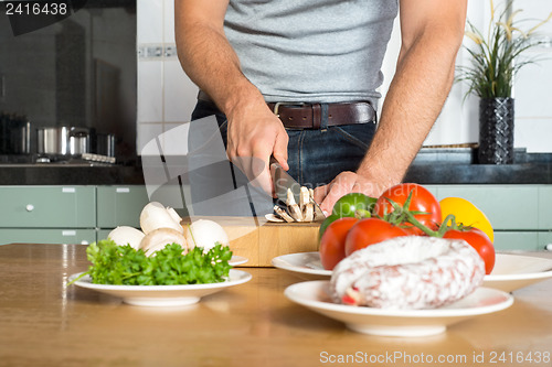 Image of Midsection Of Man Cutting Vegetables At Kitchen Counter