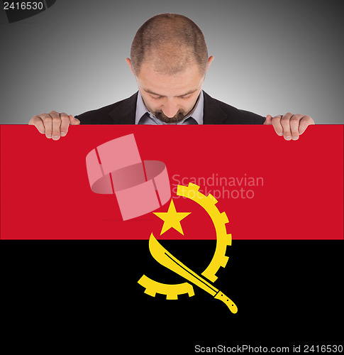 Image of Businessman holding a big card, flag of Angola