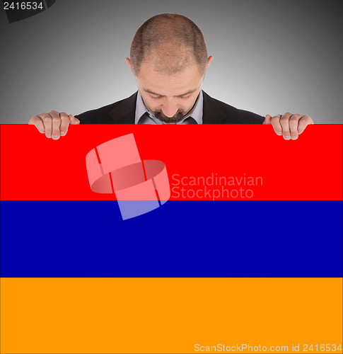 Image of Businessman holding a big card, flag of Armenia