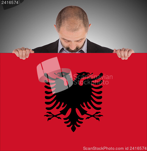 Image of Businessman holding a big card, flag of Albania