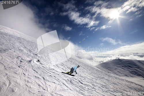 Image of Snowboarder on off-piste ski slope and blue sky with sun