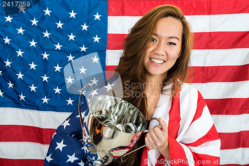 Image of Beautiful Sportswoman Holding Trophy Against North American Flag