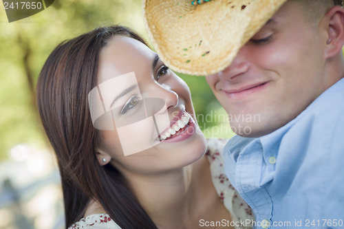 Image of Mixed Race Romantic Couple with Cowboy Hat Flirting in Park