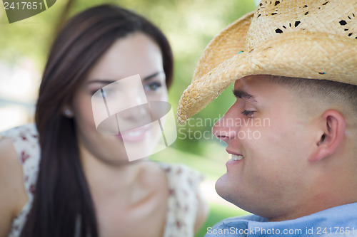 Image of Mixed Race Romantic Couple with Cowboy Hat Flirting in Park