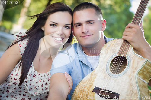 Image of Mixed Race Couple Portrait with Guitar in Park