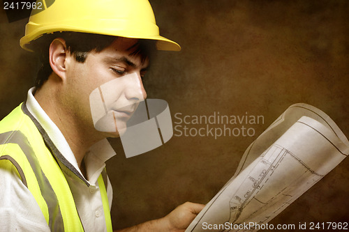 Image of Male builder site foreman reading architectural industrial plans