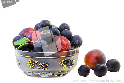 Image of Plums and prunes in a vase for fruit on a white background.