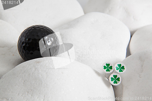 Image of Black golf ball and four leaf clovers