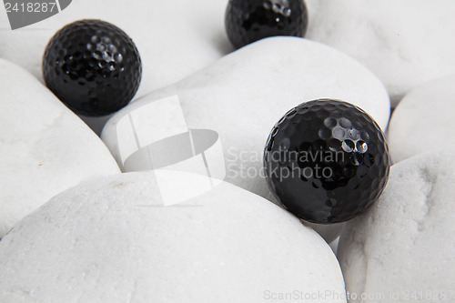 Image of Black golf balls and white stones