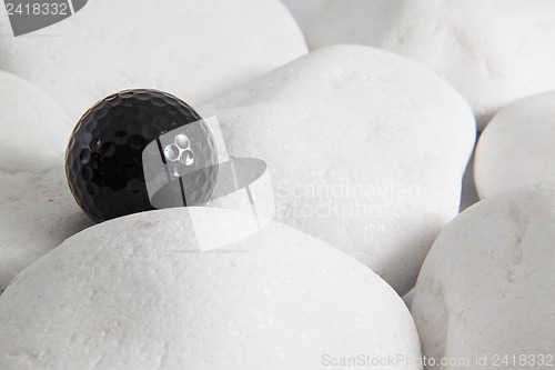 Image of Black golf ball and white stones