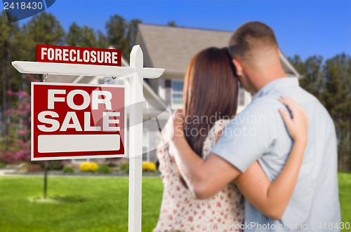 Image of Military Couple Standing in Front of Foreclosure Sign and House