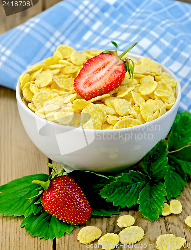 Image of Corn flakes in bowl with strawberries on a board