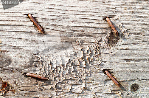 Image of textured surface of board with a rusty nail