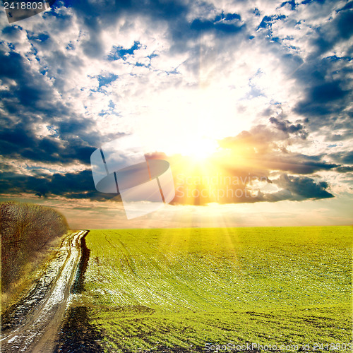 Image of sunrays over green field with path