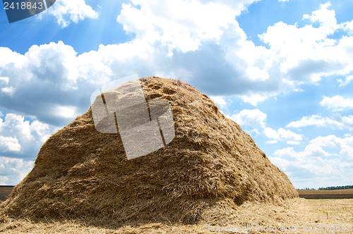 Image of stack of straw on a background blue sky with clouds
