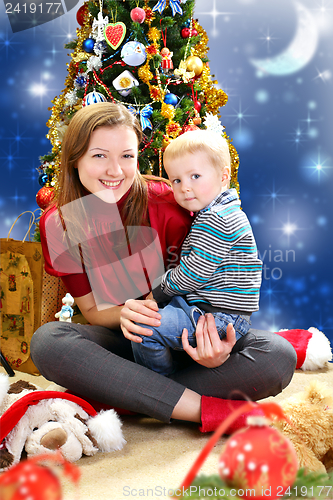 Image of Young woman with a baby near Christmas tree. 