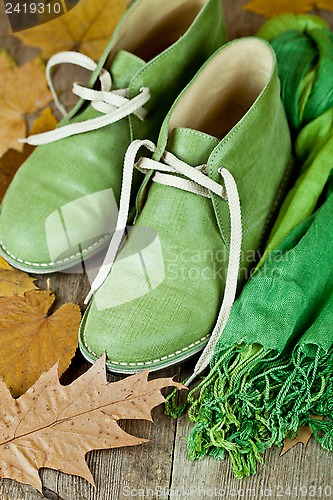 Image of pair of green leather boots, scarf and yellow leaves