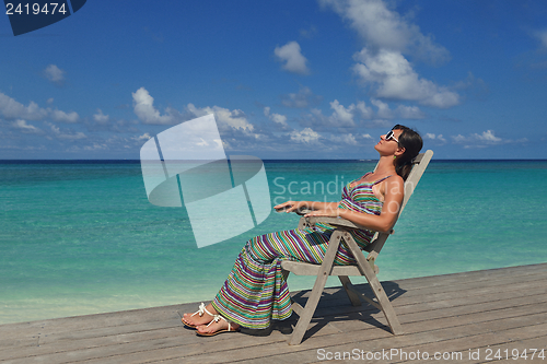 Image of Beautiful young woman with a drink by the sea