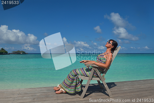 Image of Beautiful young woman with a drink by the sea