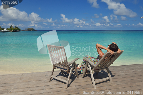 Image of Beautiful young woman with a drink by the sea