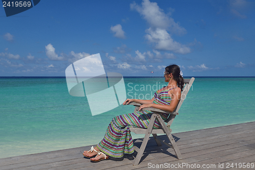 Image of Beautiful young woman with a drink by the sea