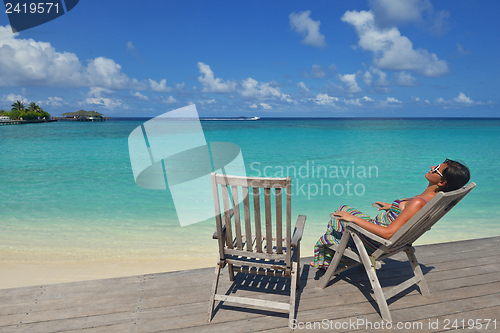 Image of Beautiful young woman with a drink by the sea